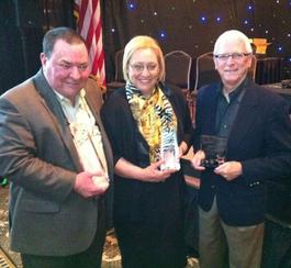 Vicki Hidde standing with two men in suits receiving 2013 Small Business Award from Tulsa Chamber of Commerce
